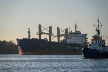 SZCZECIN, BATI POMERANYAN - 06 Kasım 2022: Bir römorkör bir yelkenliye kanal üzerinde limandan denize kadar eşlik ediyor