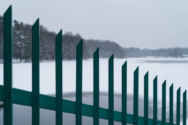 WINTER ATTACK - Steel fence on the shore of a frozen winter lake