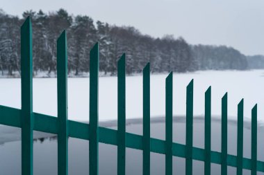 WINTER ATTACK - Steel fence on the shore of a frozen winter lake