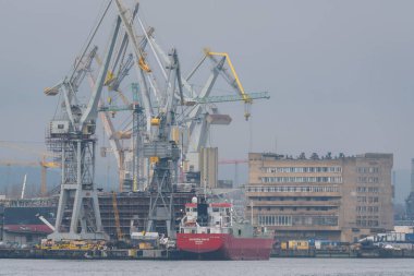 GDYNIA, POLAND - POLAND - 13 Mart 2024: Puslu bir tersanede turnalar ve gemiler