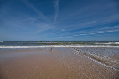 SEA Kıyı - Kumsalın üzerinde mavi gökyüzü ve deniz dalgalarıyla dolu ahşap bir çayırlık