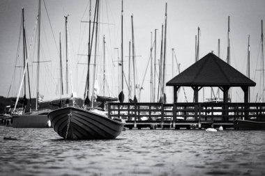 Göl kenarındaki LANDSCAPE - Marinadaki yelkenlilerin arka planına karşı küçük pembe kayık
