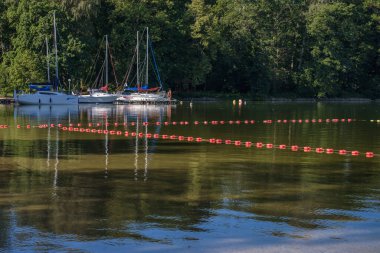 CZAPLINEK, WEST POMERANIAN - POLAND - JUNE 14, 2024: LANDSCAPE BY THE LAKE - A sailboat moored in the marina clipart