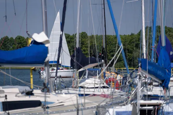 stock image CZAPLINEK, WEST POMERANIAN - POLAND - JUNE 14, 2024: LANDSCAPE BY THE LAKE - A sailboat sails on the lake and yachts in marina in the foreground