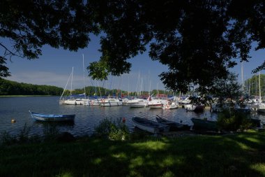 CZAPLINEK, WEST POMERANIAN - POLAND - JUNE 14, 2024: LANDSCAPE BY THE LAKE - A sailboats and motor yachts moored in the marina clipart