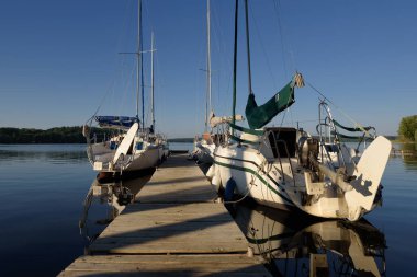 STARE DRAWSKO, BATI POLAND - 14 Haziran 2024: Göl kıyısındaki küçük bir rıhtıma demirlemiş yelkenliler