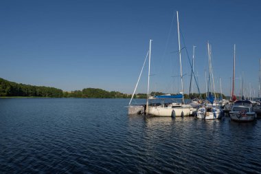 CZAPLINEK, Batı Pomeranya - POLAND - 14 Haziran 2024: LANDSCAPE Gölü 'nün yanında - marina, orman ve arka plandaki tarlalarda demirlemiş bir yelkenli