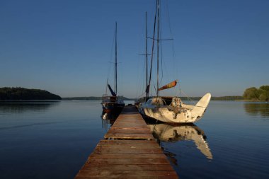 STARE DRAWSKO, WEST POMERANIAN - POLAND - JUNE 25, 2024: Sailboats moored to a pier on the lake shore clipart