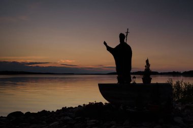 CZAPLINEK, Batı Pomeranya - POLAND - 23 Temmuz 2024: Papa II. John Paul Anıtı, günbatımında gölün arka planına karşı