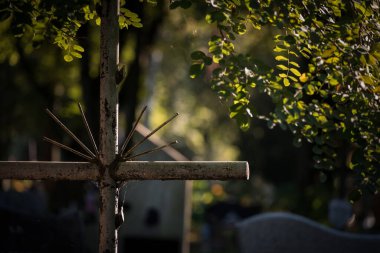 CEMETERY - An old steel cross on a tombstone clipart