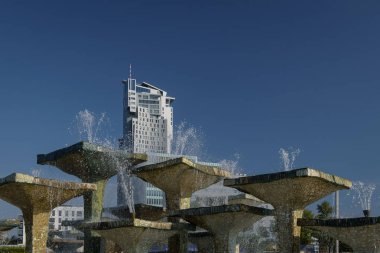 CITYSCAPE - Mavi gökyüzüne karşı bir çeşme ve prestijli bir gökdelen