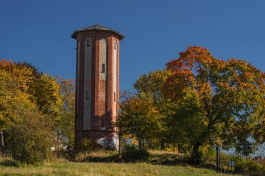 SZCZECINEK, BATI POMERANYAN - POLAND - EKİM 12. 2024: AUTUMN YÖNETMEN - Renkli ağaçların arka planına karşı tarihi bir su kulesi