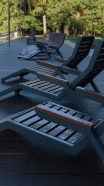 Göl kenarında dinlenme ve dinlenme - Tahta şezlong sandalyeleri Şehir parkındaki izleme platformunda sabah çiğ damlaları