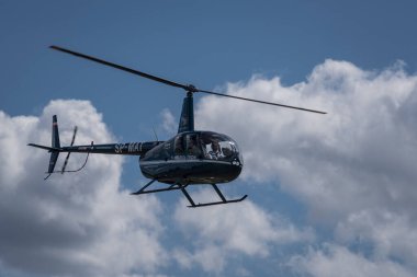BORNE SULINOWO, BATI POMERANYAN - POLAND - 11 Ağustos 2023: HELICOPTER - Kümülüs bulutlu mavi gökyüzüne karşı uçan özel makine