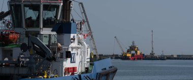 GDYNIA, POMERAN REJON - POLAND - Eylül 09, 2023: Rıhtımda bir römorkör ve arka planda çalışan bir sıkıcı