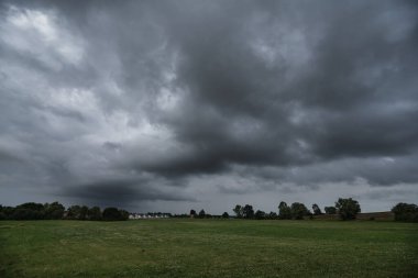 Hava - Yeşil çayır ve köy üzerinde dramatik kara yağmur bulutları