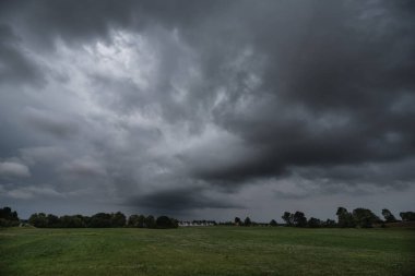 Hava - Yeşil çayır ve köy üzerinde dramatik kara yağmur bulutları