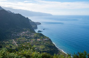 Güneşli bir günde Atlantik Okyanusu 'nun önünde yeşil tarlaları olan Madeira kıyısı.