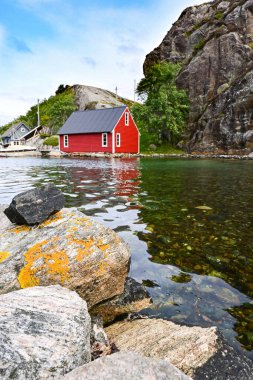 Norveç 'in kuzeyindeki Bergen yakınlarındaki fiyordun kıyısındaki güzel kırmızı ahşap kulübe.