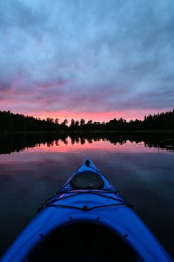 Sihirli bir günbatımı akşamında doğal bir Norveç gölü üzerinde Kano 'dan ilk kişi görüntüsü