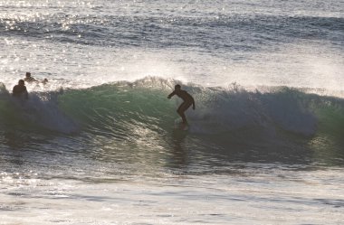 Genç sörfçü Caos de Meca 'da el sallıyor. Cadiz 'deki İspanyol Atlantik kıyısı, Avrupa' da mükemmel bir sörf noktası.
