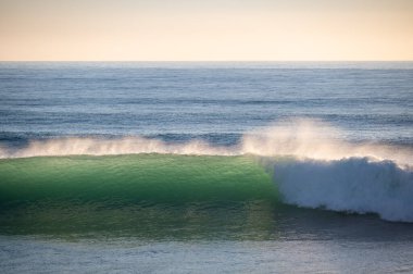 Güney İspanya 'da bir kış akşamı güzel Atlantik dalgaları kopuyor. Sörfçü dalgalar nazikçe kırılıyor