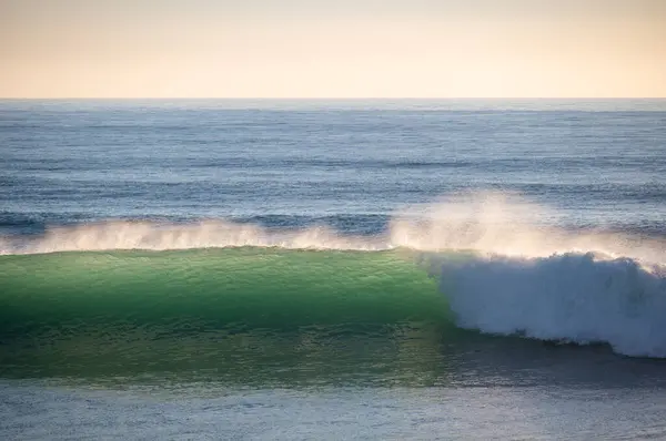 Güney İspanya 'da bir kış akşamı güzel Atlantik dalgaları kopuyor. Sörfçü dalgalar nazikçe kırılıyor