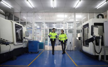  Supervisor Consults Young Engineer Working with big machine 