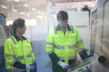  Supervisor Consults Young Engineer Working with big machine 