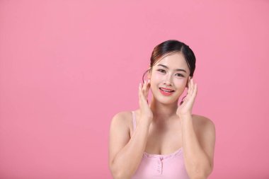 Pembe arka plan, yüz ve cilt bakımında temiz, genç Asyalı güzel bir kadın.
