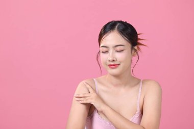 Pembe arka plan, yüz ve cilt bakımında temiz, genç Asyalı güzel bir kadın.
