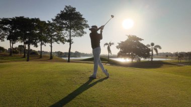 İnsanlar güzel bir sahada golf oynuyor, salıncak ve golf topuna vuruyor, lüks bir tatil.