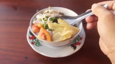 Bir kase soto ayam veya tavuk çorbası. Tahta masada tipik Endonezya yemeği.
