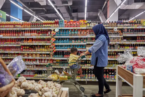 Süpermarkette tesettür takan Asyalı kadın, mağaza rafları arasında günlük ihtiyaçlarını arıyor