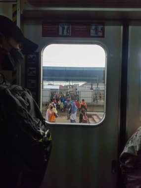 Trendeki tren yolcusu pencereden istasyona bakıyor.