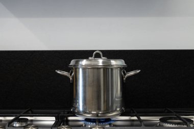 Pişirdiğin tencereyi kapakla kapat. Ocakta pişirmek için çelik kap kaplıdır. Doğal gaz krizi ve küresel ısınma nedeniyle gerekli enerji tasarrufu için iyi uygulamalar kavramı.