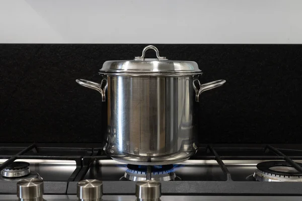 Cover a pot you are cooking with with a lid. Steel pot comes covered for cooking on gas stove. Concept for good practices for the energy saving needed due to the natural gas crisis and global warming.