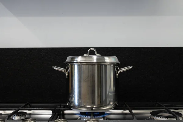Cover a pot you are cooking with with a lid. Steel pot comes covered for cooking on gas stove. Concept for good practices for the energy saving needed due to the natural gas crisis and global warming.