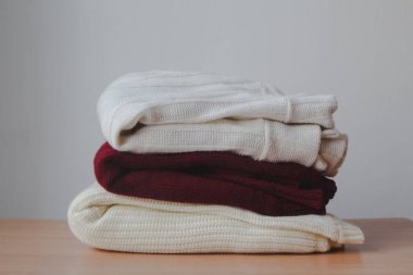 Temiz, yeni yıkanmış bir yığın, masaya kazak yığını, beyaz duvar arka planı. Boşluğu kopyala, kapat,