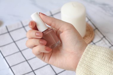 Kadın masadaki ojeyi, el bakımını, elleri ve kaplıcayı gösteriyor.,