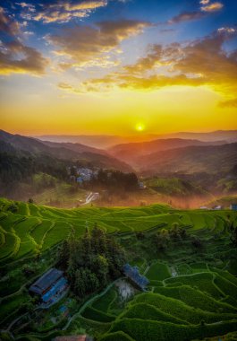 Tang 'an Dong Köyü, Liping County, Guizhou, Çin' deki ünlü Zhaoxing Dong Köyü 'nün yanındaki teraslı tarlaların günbatımı manzarası..