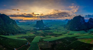 Daxin County, Guangxi, Çin 'in günbatımı manzarası. Tepeleri, ormanları ve tarlaları alacakaranlık parıltısıyla yıkanmış..