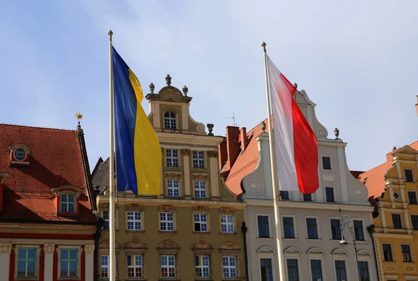 Wroclaw, Poland- April 14, 2022: The state flags of Poland and Ukraine flutter on flagpoles on the main square of the city. Friendship between Poland and Ukraine, Help and Solidarity