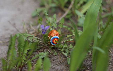 Easter egg hunt. Colorful Easter eggs and the Easter bunny are hidden in the garden and flower beds among the flowers, trees and gravel paths. Holiday traditions. Easter card, banner. Selective focus clipart