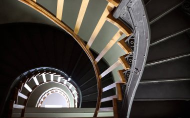 Wroclaw 'daki eski bir binada ahşap korkuluklu yarım sarmal merdiven. Aşağıdan yukarıdaki ışığa bak. Altın bölüm, güzel arkaplan