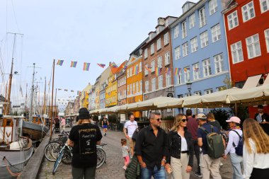 Kopenhag, Danimarka - 17 Ağustos 2023: Nyhavn Kanalı. Nyhavn rıhtımında gezen turistler eski mimari binalarında barlar ve restoranlarla birlikte tekne turu yapıyorlar.