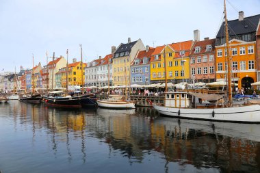 Kopenhag, Danimarka - 17 Ağustos 2023: Nyhavn Kanalı. Nyhavn rıhtımında gezen turistler eski mimari binalarında barlar ve restoranlarla birlikte tekne turu yapıyorlar.