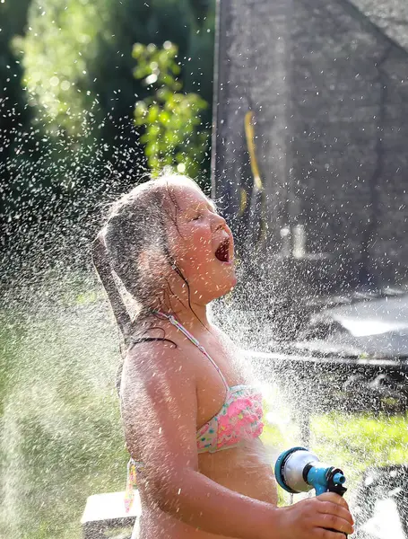 kid girl splatter with water to cool off in summer vacations. cheerful happy kid