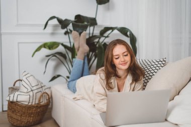 Young pretty redhad woman student using laptop elearning or remote working at home office looking at laptop computer watching webinar, learning virtual class, having video call hybrid meeting