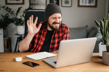 Happy indian professional business man teacher, business coach or hr manager waving hand remote working by video call, having hybrid office online meeting, leading training or webinar elearning class.